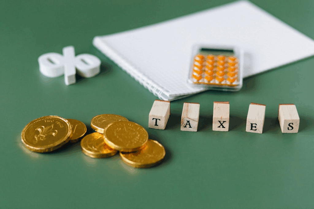 Tax planning concept with gold coins, calculator, and the word "TAXES" spelled out on wooden blocks