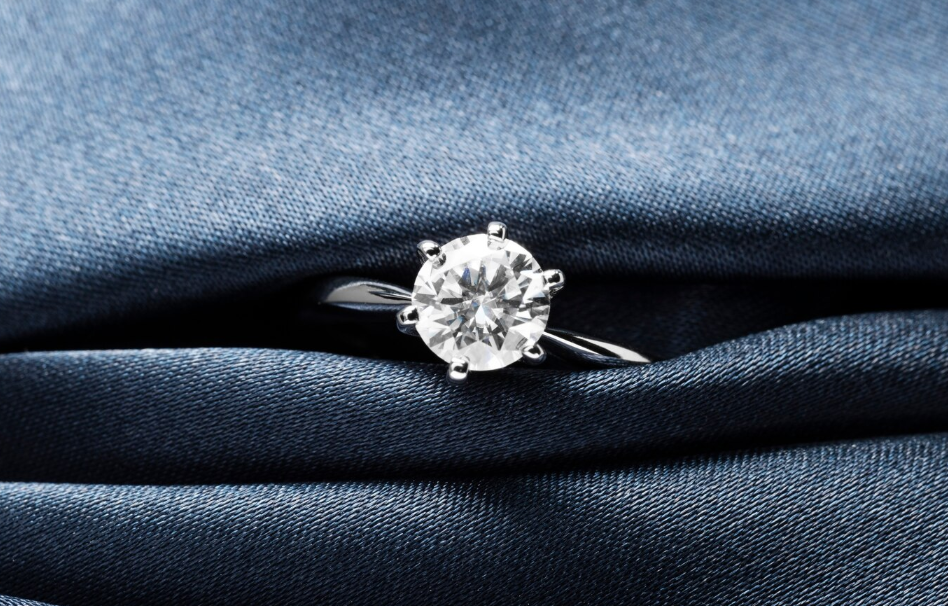 Close-up of a luxury diamond ring on folded blue silk fabric