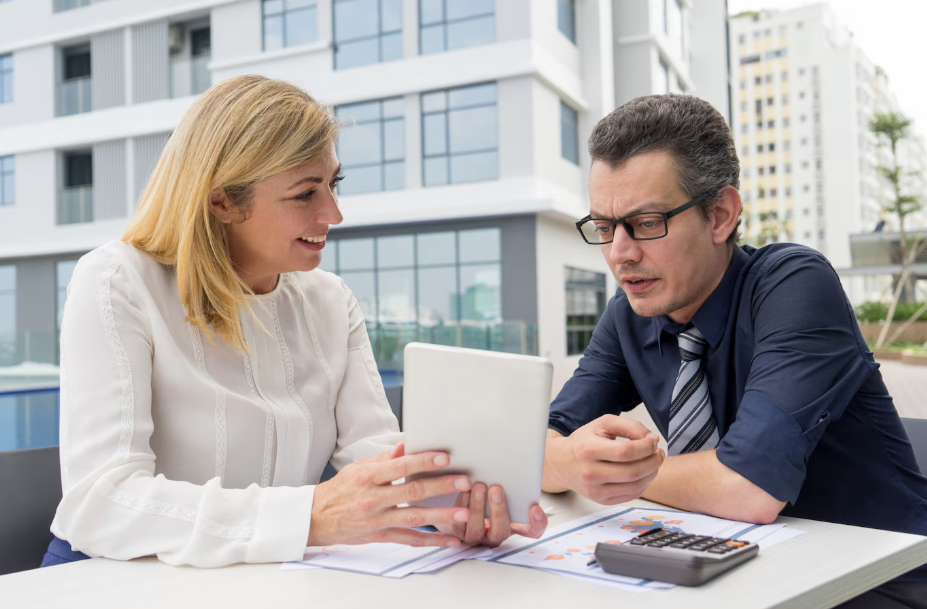 Financial advisor discussing investment strategy with a client using a tablet in an outdoor office setting